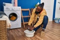 Young african american man talking on the smartphone cleaning cloth on cube with water at laundry room