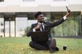 African-American man using laptop outdoors, sitting on the grass near office Royalty Free Stock Photo