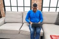 Young african american man using laptop sitting on sofa at home Royalty Free Stock Photo