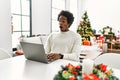 Young african american man using laptop sitting on the table by christmas tree afraid and shocked with surprise expression, fear Royalty Free Stock Photo
