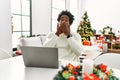 Young african american man using laptop sitting on the table by christmas tree shocked covering mouth with hands for mistake Royalty Free Stock Photo