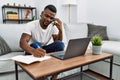Young african american man using laptop talking on the smartphone at home Royalty Free Stock Photo