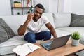 Young african american man using laptop talking on the smartphone at home Royalty Free Stock Photo