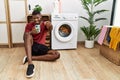 Young african american man using smartphone waiting for washing machine pointing fingers to camera with happy and funny face Royalty Free Stock Photo