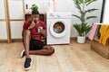 Young african american man using smartphone waiting for washing machine pointing to the eye watching you gesture, suspicious Royalty Free Stock Photo