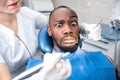 Young african-american man visiting dentist`s office, looks scared