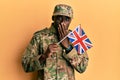 Young african american man wearing army uniform holding united kingdom flag covering mouth with hand, shocked and afraid for Royalty Free Stock Photo