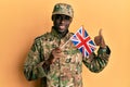 Young african american man wearing army uniform holding united kingdom flag smiling happy and positive, thumb up doing excellent Royalty Free Stock Photo