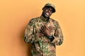 Young african american man wearing army uniform smiling with hands on chest with closed eyes and grateful gesture on face