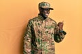 Young african american man wearing army uniform smiling with happy face looking and pointing to the side with thumb up Royalty Free Stock Photo