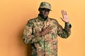 Young african american man wearing army uniform swearing with hand on chest and open palm, making a loyalty promise oath