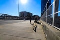 A young African American man wearing a black hoodie walking along a wide smooth sidewalk along a street with glass office building Royalty Free Stock Photo