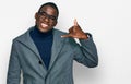 Young african american man wearing business clothes and glasses smiling doing phone gesture with hand and fingers like talking on Royalty Free Stock Photo