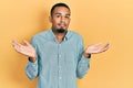 Young african american man wearing casual clothes clueless and confused expression with arms and hands raised Royalty Free Stock Photo