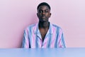 Young african american man wearing casual clothes sitting on the table relaxed with serious expression on face Royalty Free Stock Photo