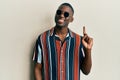 Young african american man wearing casual clothes and sunglasses smiling with an idea or question pointing finger up with happy Royalty Free Stock Photo