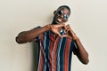 Young african american man wearing casual clothes and sunglasses smiling in love doing heart symbol shape with hands Royalty Free Stock Photo