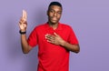 Young african american man wearing casual red t shirt smiling swearing with hand on chest and fingers up, making a loyalty promise Royalty Free Stock Photo