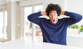 Young african american man wearing casual sweater sitting at home Crazy and scared with hands on head, afraid and surprised of Royalty Free Stock Photo