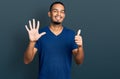 Young african american man wearing casual t shirt showing and pointing up with fingers number six while smiling confident and Royalty Free Stock Photo