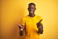 Young african american man wearing casual t-shirt standing over isolated yellow background smiling confident pointing with fingers Royalty Free Stock Photo