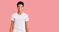 Young african american man wearing casual white t shirt looking positive and happy standing and smiling with a confident smile Royalty Free Stock Photo