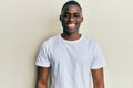 Young african american man wearing casual white t shirt looking positive and happy standing and smiling with a confident smile Royalty Free Stock Photo