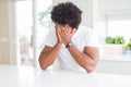 Young african american man wearing casual white t-shirt sitting at home with sad expression covering face with hands while crying Royalty Free Stock Photo
