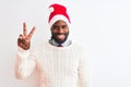 Young african american man wearing Christmas Santa hat over isolated white background smiling with happy face winking at the Royalty Free Stock Photo