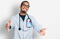 Young african american man wearing doctor uniform and stethoscope looking at the camera smiling with open arms for hug Royalty Free Stock Photo