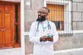 Young african american man wearing doctor uniform using smartphone at hospital Royalty Free Stock Photo