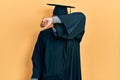 Young african american man wearing graduation cap and ceremony robe covering eyes with arm smiling cheerful and funny Royalty Free Stock Photo