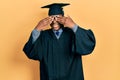 Young african american man wearing graduation cap and ceremony robe covering eyes with hands smiling cheerful and funny Royalty Free Stock Photo