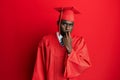 Young african american man wearing graduation cap and ceremony robe looking stressed and nervous with hands on mouth biting nails Royalty Free Stock Photo