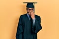Young african american man wearing graduation cap and ceremony robe looking stressed and nervous with hands on mouth biting nails Royalty Free Stock Photo