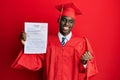 Young african american man wearing graduation cap and ceremony robe showing passed exam screaming proud, celebrating victory and Royalty Free Stock Photo