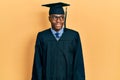 Young african american man wearing graduation cap and ceremony robe smiling looking to the side and staring away thinking Royalty Free Stock Photo