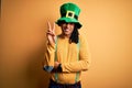 Young african american man wearing green hat celebrating saint patricks day smiling with happy face winking at the camera doing