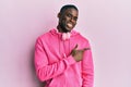 Young african american man wearing gym clothes and using headphones cheerful with a smile of face pointing with hand and finger up Royalty Free Stock Photo