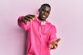 Young african american man wearing gym clothes and using headphones looking at the camera smiling with open arms for hug Royalty Free Stock Photo