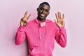 Young african american man wearing gym clothes and using headphones showing and pointing up with fingers number eight while Royalty Free Stock Photo