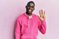 Young african american man wearing gym clothes and using headphones showing and pointing up with fingers number five while smiling Royalty Free Stock Photo