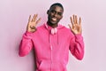 Young african american man wearing gym clothes and using headphones showing and pointing up with fingers number nine while smiling Royalty Free Stock Photo