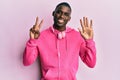 Young african american man wearing gym clothes and using headphones showing and pointing up with fingers number seven while Royalty Free Stock Photo