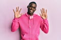 Young african american man wearing gym clothes and using headphones showing and pointing up with fingers number ten while smiling Royalty Free Stock Photo