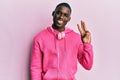 Young african american man wearing gym clothes and using headphones showing and pointing up with fingers number three while Royalty Free Stock Photo