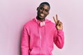 Young african american man wearing gym clothes and using headphones showing and pointing up with fingers number two while smiling Royalty Free Stock Photo