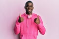 Young african american man wearing gym clothes and using headphones success sign doing positive gesture with hand, thumbs up Royalty Free Stock Photo