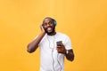 Young African American man wearing headphone and enjoy music over yellow gold Background Royalty Free Stock Photo