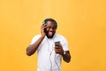 Young African American man wearing headphone and enjoy music over yellow gold Background Royalty Free Stock Photo